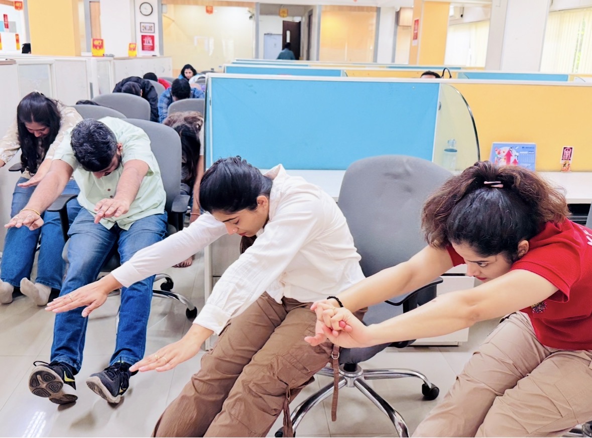 Employees taking part in a seated workplace wellness exercise